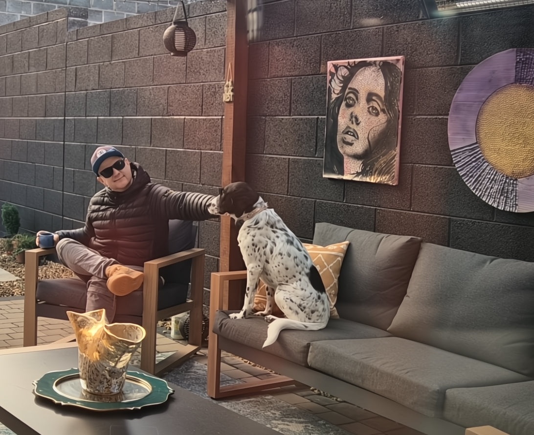 Person sitting on a chair with a dog on a couch in an outdoor patio area.